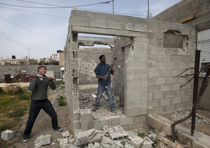Palestinian Motasem Farrah (center) and a friend tear down Farrah's home in an Arab neighborhood in east Jerusalem, March 12. Israel often tells Palestinians who build without permits that they must tear down the house themselves or they will be charged by Israel for the cost of knocking it down.