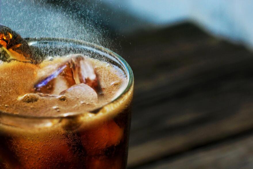 A glass of soda with ice cubes.