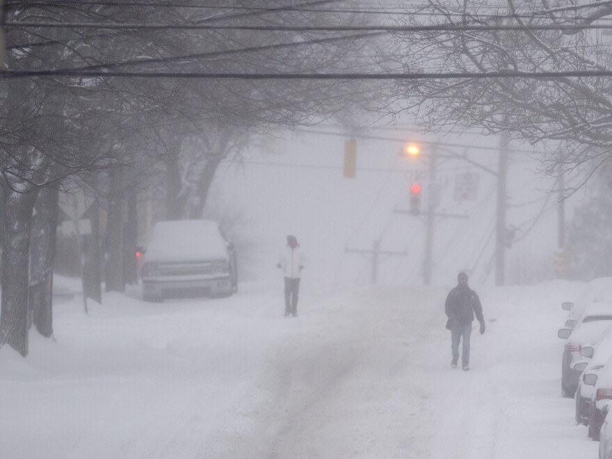 Pedestrians make their way down a partially plowed Murray Avenue Monday, Jan. 17, 2022, in Squirrel Hill neighborhood of Pittsburgh.