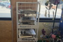 An in-store newsstand with stacks of newspapers placed inside of a window.