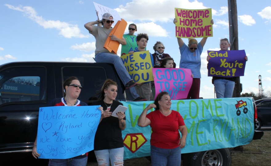 Melissa Salinas and her family and friends decorated a truck to welcome Ryland Ward home from the hospital. Terrie Smith, right, and other neighbors peer down the road in anticipation of his arrival Jan. 11.