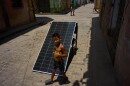 A child walks with a bottle of oil past a solar panel set up on the street to charge batteries during a blackout in Havana, Cuba, Monday, July 6, 2026.