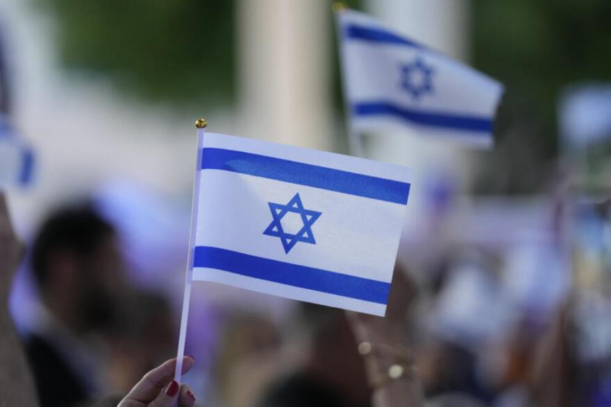 People wave Israeli flags during an empty Shabbat table event honoring those kidnapped by Hamas in Israel, Thursday, Nov. 2, 2023, at Temple Beth Sholom in Miami Beach, Florida. (Wilfredo Lee/AP)