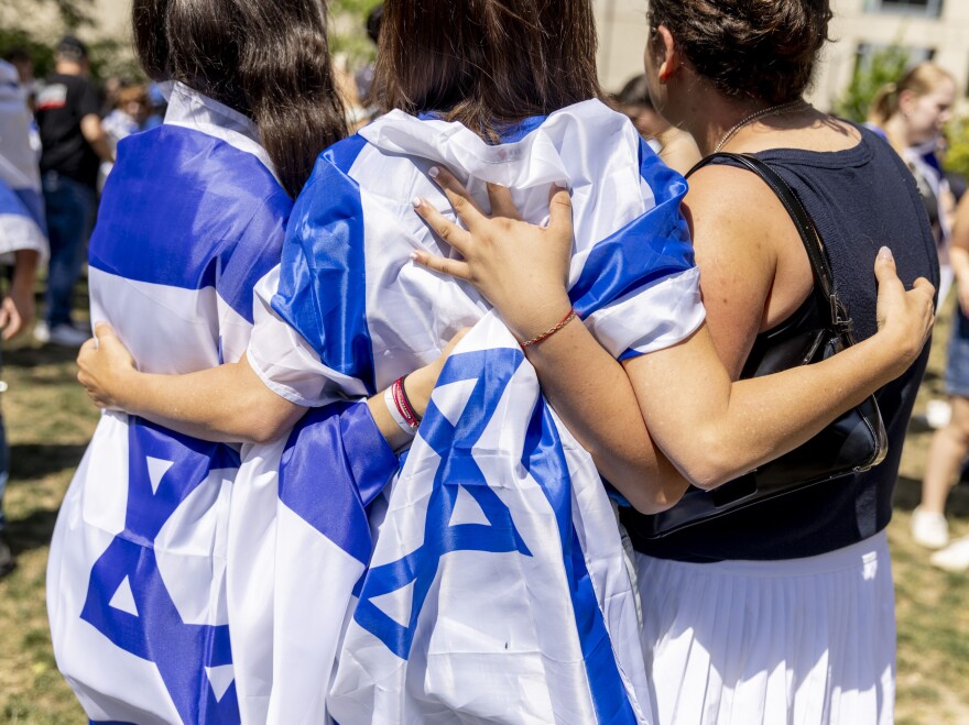 Pro-Israel counter-protestors draped in Israeli flags embrace at George Washington University.