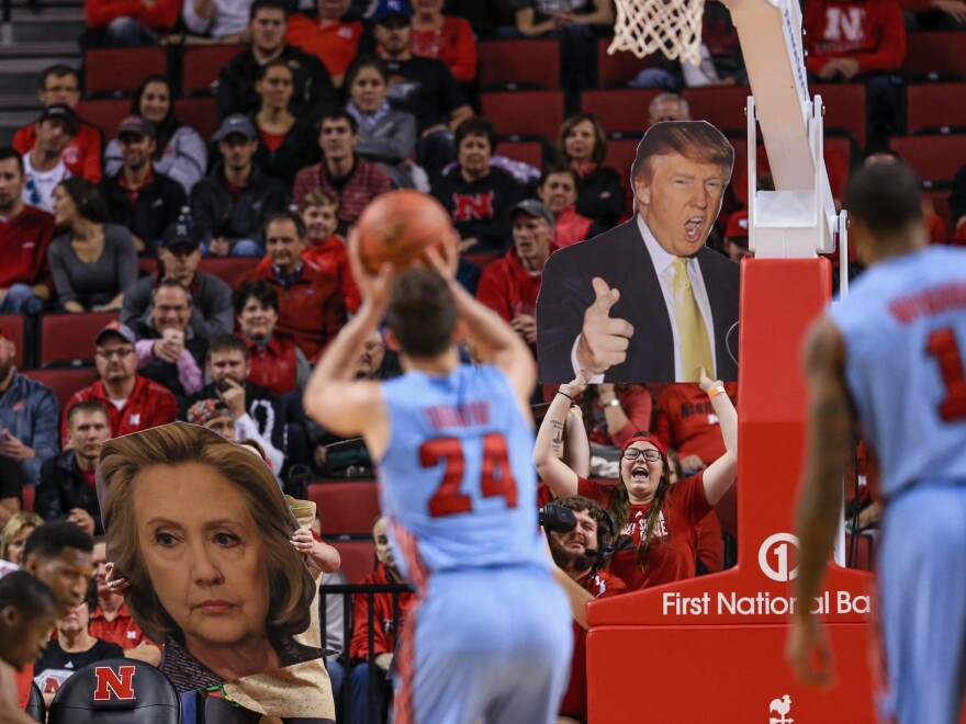Nebraska basketball fans wave signs with the images of Donald Trump and Hillary Clinton. Nebraska neighbors Iowa, where Clinton and Trump are narrowly ahead days before the caucuses there.
