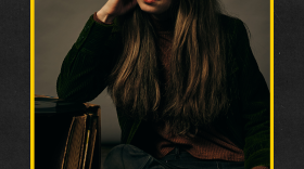 Photo of Chelsea O sitting with her head resting in her right hand with a yellow border around the photo over a black-ish background