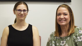 Two women smile for a photo during an interview held in a public radio station studio.  