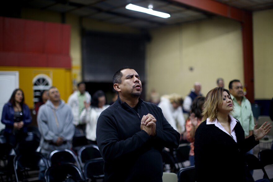 Pastor Robert Salazar (center) prays before giving his sermon at the "Cruising for Jesus" mission of Tijuana. Salazar's church also runs a men's drug-rehab shelter nearby to help deported veterans.