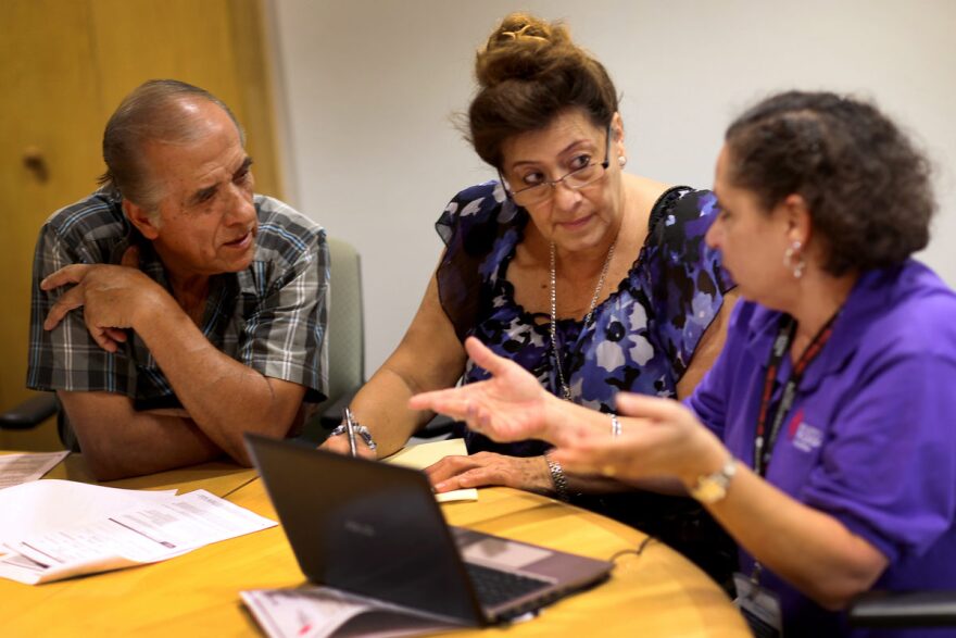 Affordable Care Act navigator Nini Hadwen (right) helped Jorge Hernandez (left) and Marta Aguirre find a plan on the health insurance exchange in Miami in 2013. Today, with fewer navigators, much of that counseling is done by phone instead of in pers