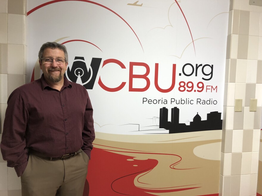 Greater Peoria Economic Development Council CEO Chris Setti stands in front of the mural in the WCBU Newsroom.