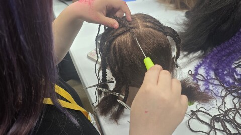 Student crocheting hair into the mannequin head.