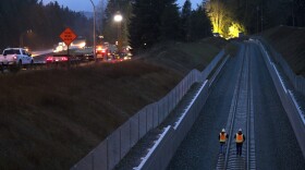 Workers walk along the rail line near the scene of the derailment on Monday in Dupont. 