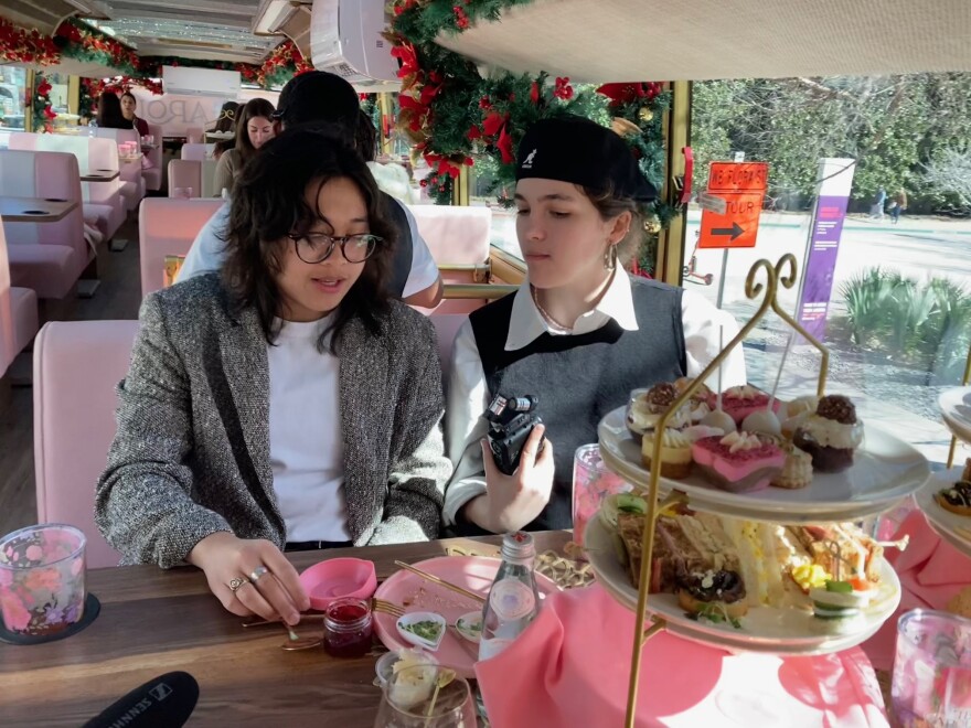 Criselle Velasco (left) and KERA's Alexsis Jones sample the food on the Tea Around Town bus.