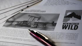 A pen lies on an audit form that features an oil well.
