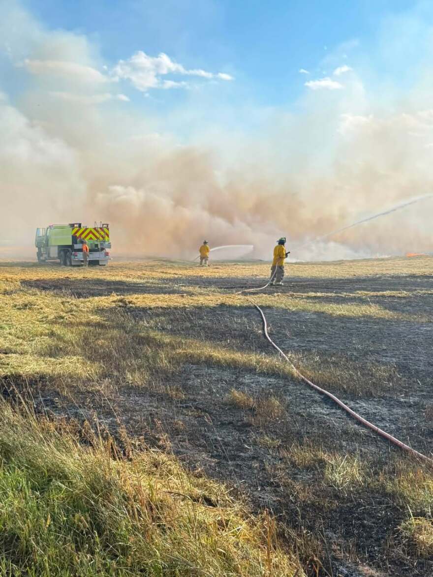 Firefighters extinguish a blaze at a hay field in the Eagle River area