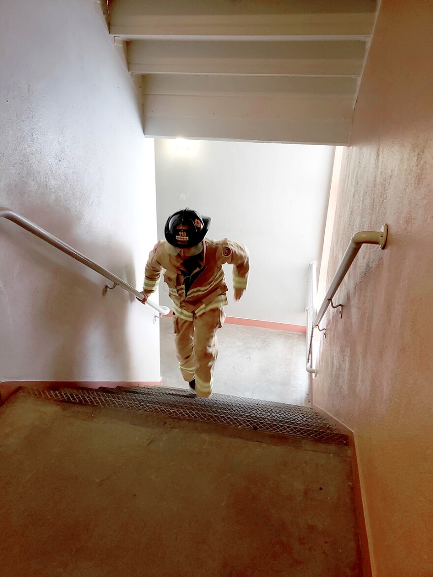 Missoula Firefighter Andy Drobeck running stairs in his helmet, boots, jacket and pants in one of Aber Hall's stairwells on the University of Montana's campus.