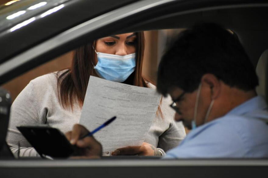 A human resources representative reads a resume at a drive-thru job fair in Elkhart.