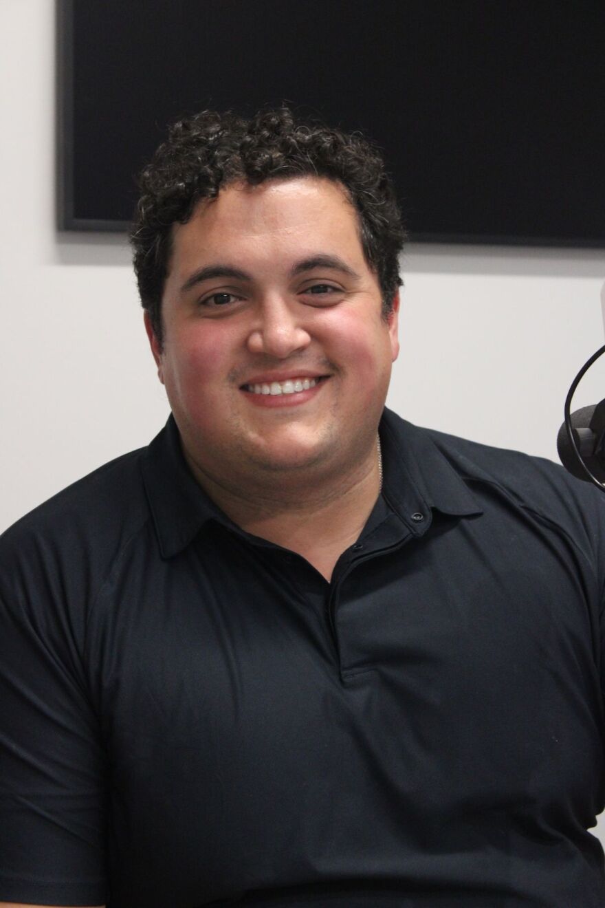 A headshot photo of a man with curly hair and in a polo
