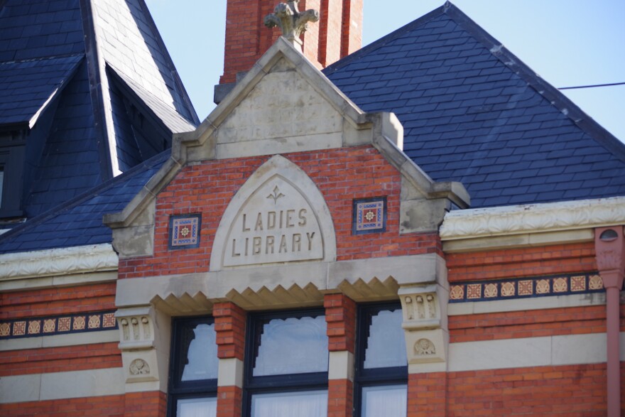 A stone carving on a red brick building reads "Ladies Library"