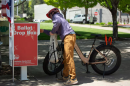 A person standing next to a bicycle reaching towards a ballot box.