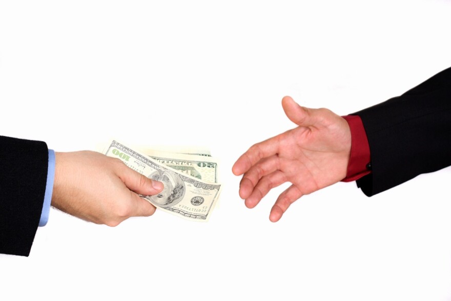 Closeup of a hand reaching to take money from another hand