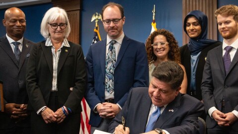 Gov. JB Pritzker signs the Artificial Intelligence Safety Measures Act into law in Chicago on July 6, 2026, surrounded by lawmakers and advocates.