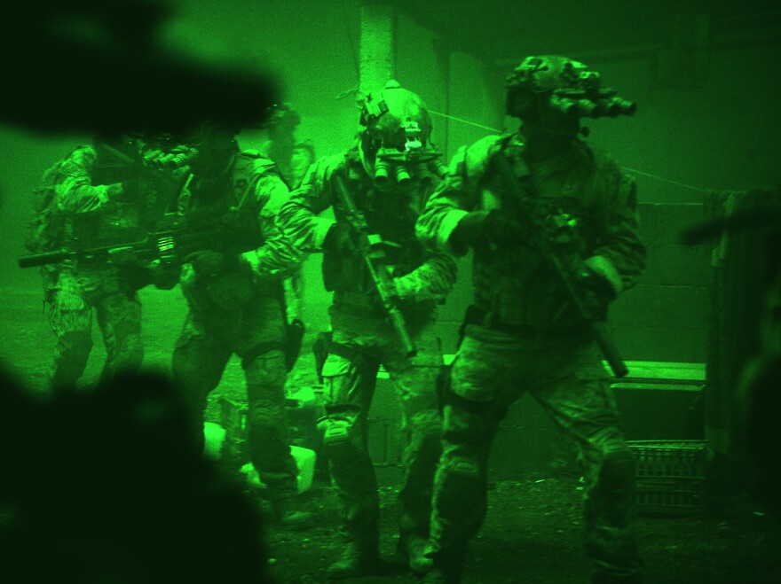 Seen through the greenish glow of night-vision goggles, Navy SEALs prepare to breach a locked door in Osama bin Laden's compound in <em>Zero Dark Thirty</em>.
