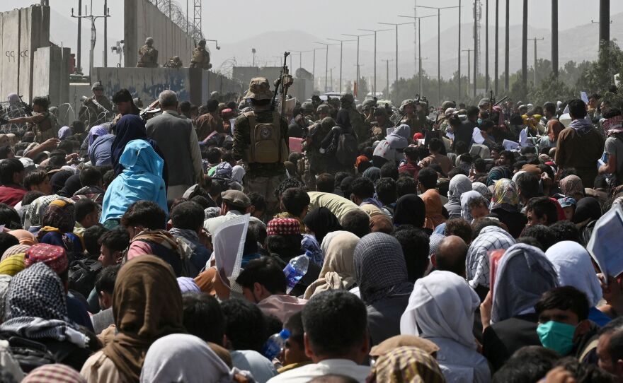 Afghans gather on a roadside near the military part of the airport in Kabul hoping to flee from Afghanistan after the Taliban's military takeover of country.