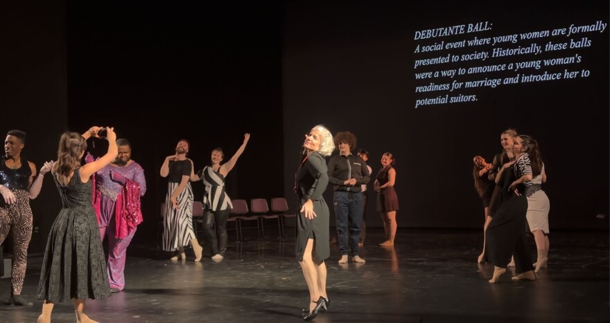 In the ball scene, the cast is frozen in frame as a screen on stage displays a description of a traditional debutante ball.