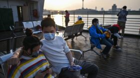 People wearing face masks ride a ferry to cross the Yangtze River in Wuhan in China's central Hubei province after restrictions to halt the COVID-19 coronavirus were lifted.