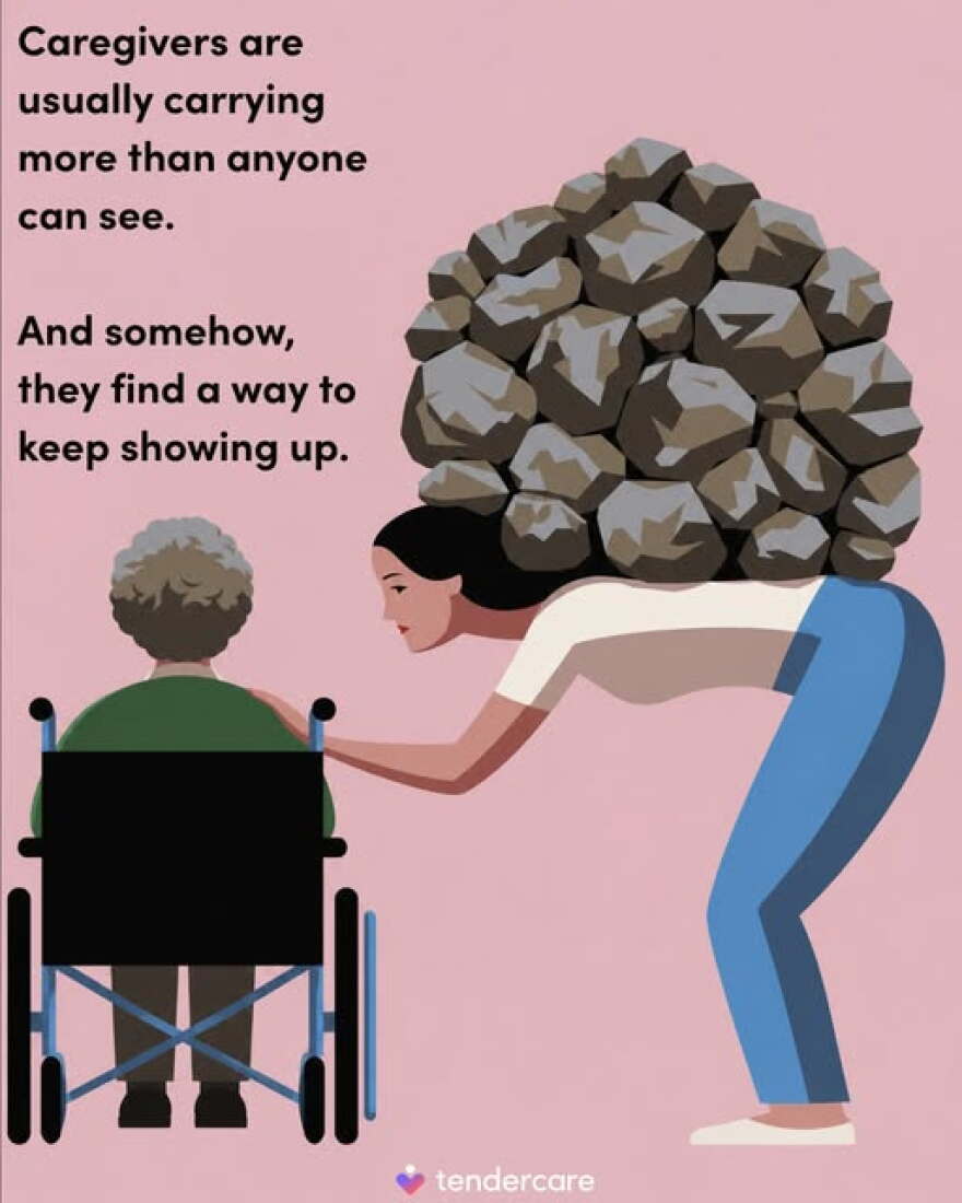 A women in blue pants and a white shirt stands hunched over with a pile of rocks on her back as she has he head on a older women's shoulder in a wheelchair wearing a green shirt. 