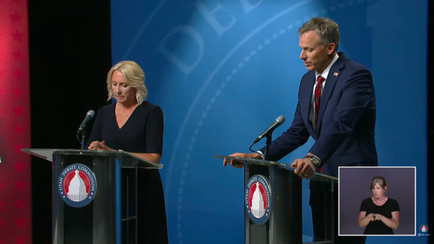 Incumbent Blake Moore and Rep. Karianne Lisonbee stand behind podiums on stage. 