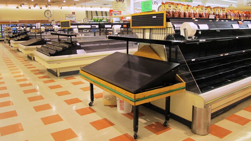 The aisles and food cases are largely empty inside a Market Basket in Somerville, Mass. Workers have disrupted operations by leaving produce to spoil in the back of the store and parking semitrucks to block loading bays.