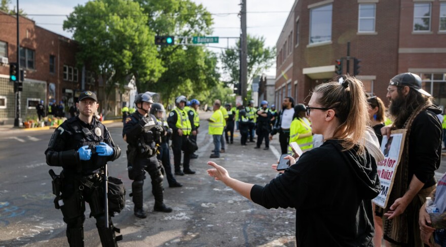 A protester confronts a Madison police officer standing in the intersection where Corey Ruiz was shot and killed by an officer as the police and other workers clean the area and re-open it to traffic Tuesday, Aug. 4, 2026, in Madison, Wis.