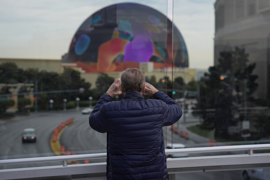 A person stops to take a picture of the Sphere on a pedestrian bridge along the Las Vegas Strip, Wednesday, Jan. 17, 2024, in Las Vegas.