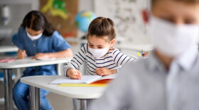 Children with face masks in a school classroom.