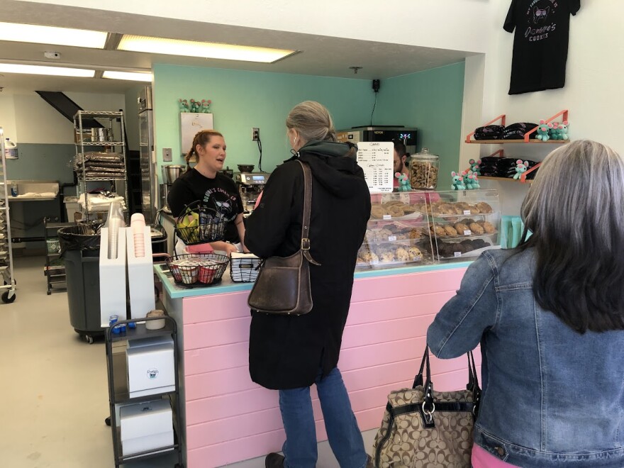 Customers line up on Doughmo's Cookie Company's grand opening day, as Kodie Dorman works the cashier.