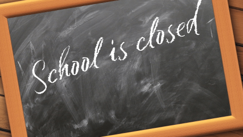 A black chalk board with the writing, school closed on it.