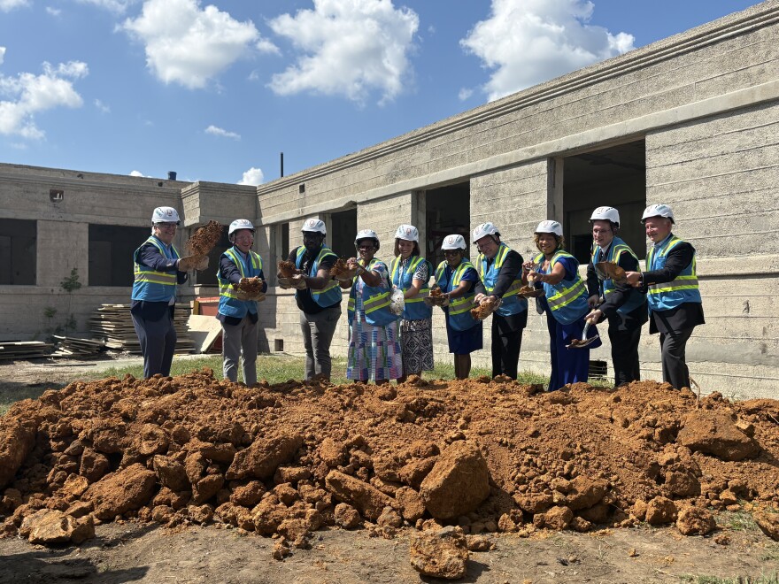 Birmingham city leaders and representatives of Christ Health Center and The Salvation Army in construction attire use shovels to break ground at the clinic's construction site.