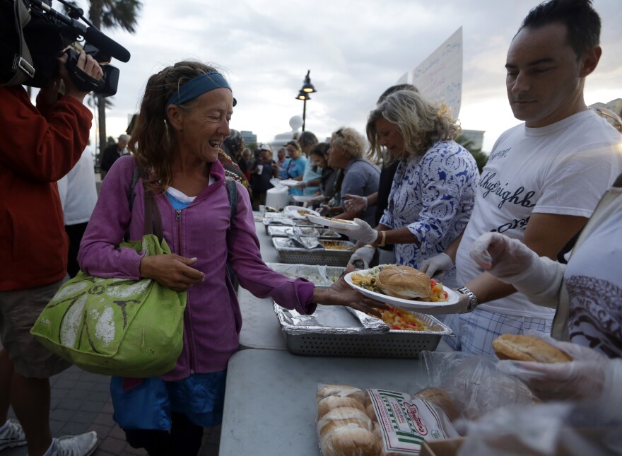 Volunteers working with the late Arnold Abbott feed the homeless at a public parking lot on Nov. 5, 2014, in Fort Lauderdale, Fla. Abbott, then director of nonprofit Love Thy Neighbor Inc., was cited for violating an ordinance that limited where charitable groups can feed the homeless on public property. The ordinance, since lifted, is now at the center of a costly lawsuit for the city.