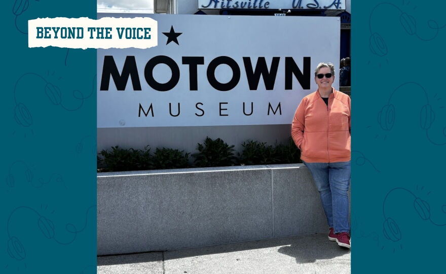 A woman wearing sunglasses smiles next to the Motown Museum sign.