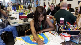 Priscilla Miller, who has been coming to Artists First for about a year, colors in one of her drawings.