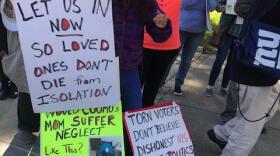 At a protest outside the state Capitol, Mary Beth Delarm displays pictures of her mother, who died in a nursing home in May during the COVID-19 pandemic CREDIT KAREN DEWITT / WRVO NEWS
