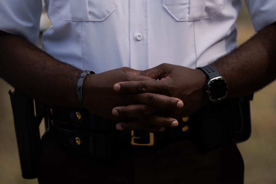 A St. Louis County police officer stands at attention during a press conference after a series of home explosions damaged more than a dozen residences on Monday, Aug. 25, 2025, near Black Jack.