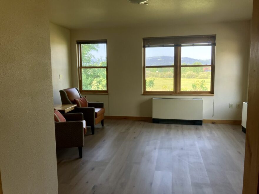 Two chairs sit near windows, looking upon rolling fields.