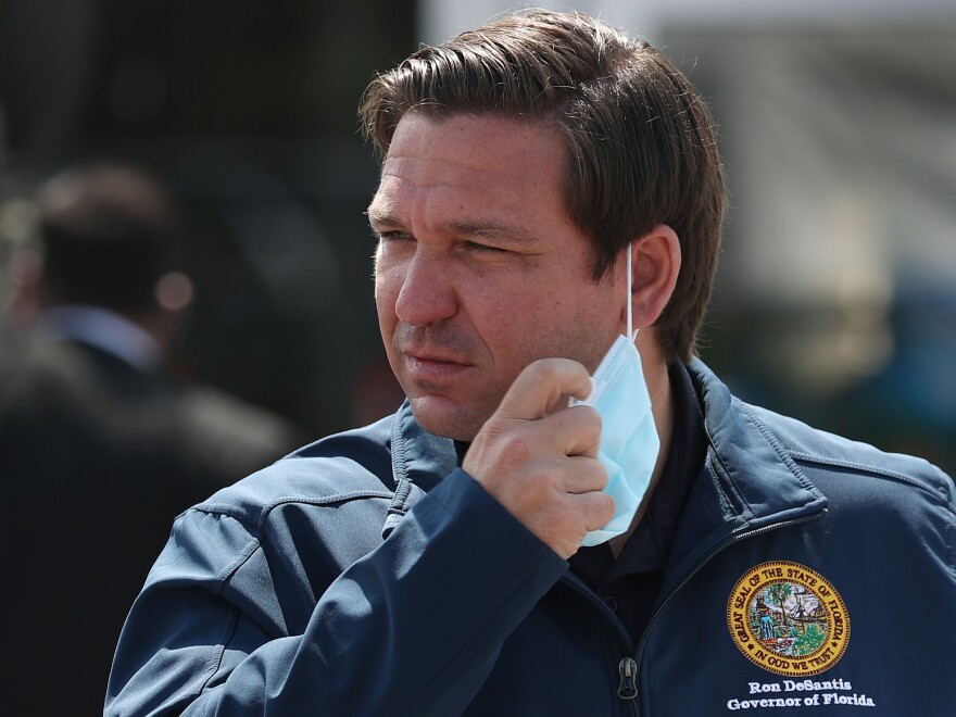 Florida Gov. Ron DeSantis takes his mask off as he prepares to speak during a press conference at the Hard Rock Stadium testing site on May 06, 2020 in Miami Gardens, Fla.