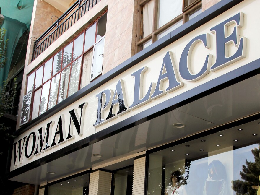 An Afghan woman walks past Woman Palace, which recently opened in Kabul. Despite the country's poverty and traditional, modest dress, stores catering to wedding gowns and other upscale women's clothing are doing a brisk business.