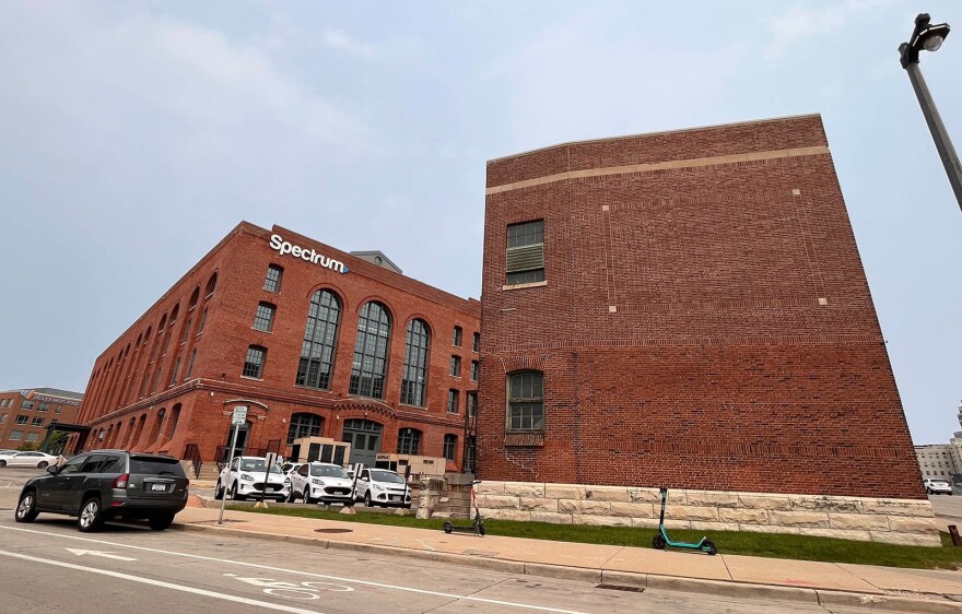  The exterior of two all-brick, four-story buildings with tall windows against a blue sky.