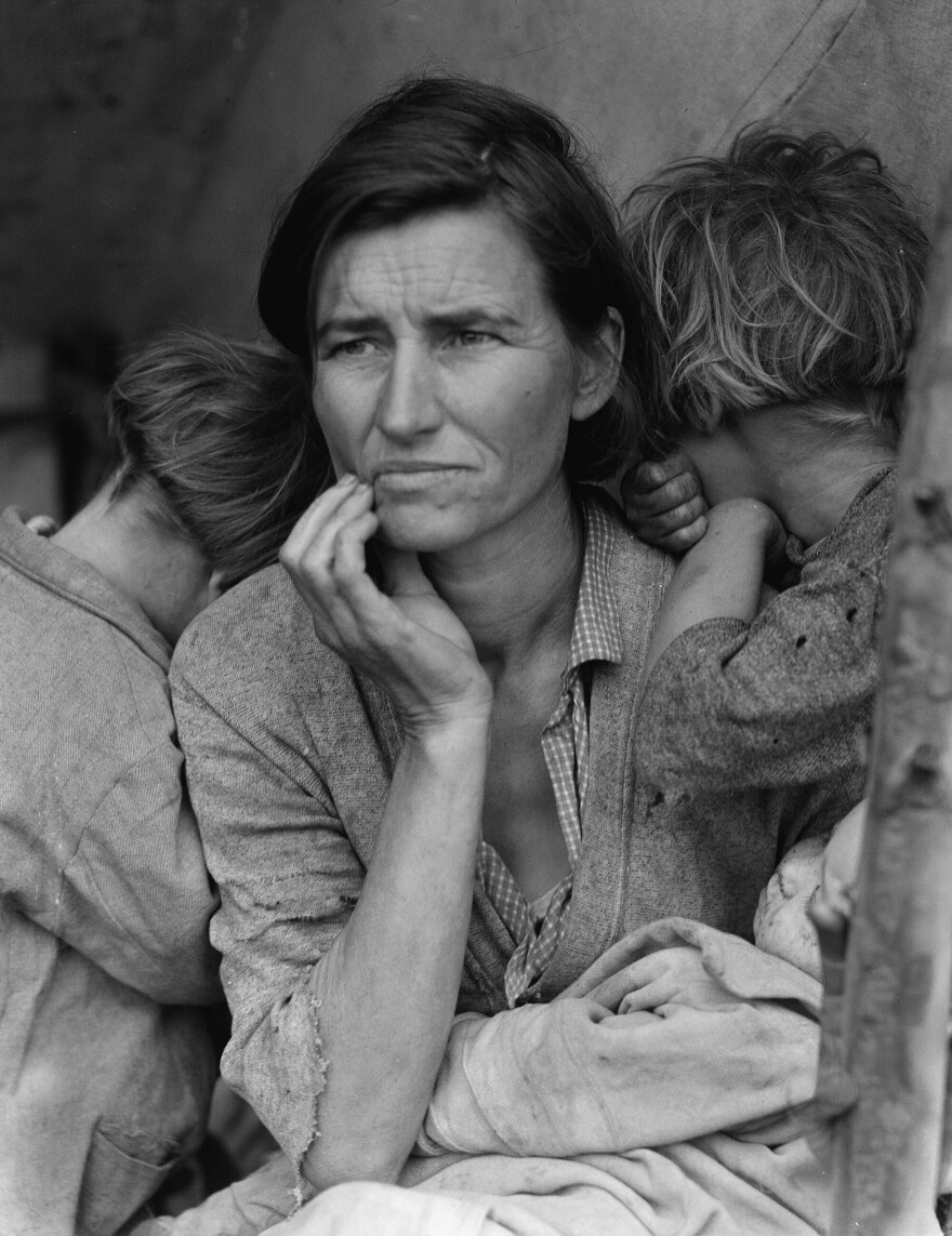A black and white image of a depression era woman flanked by two children.