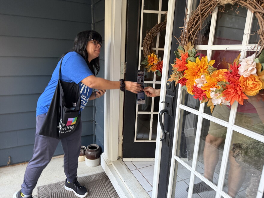 Melissa Molina, a member of Grassroots Resistance, hands literature about candidates the organization supports to a resident in Bay Village a week before the election.